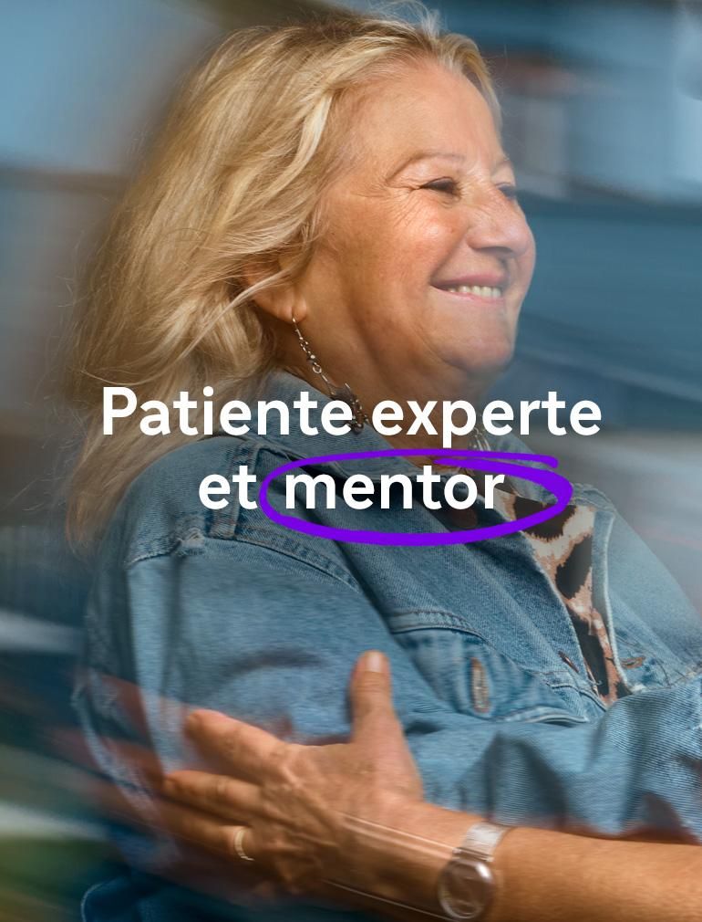 Une femme souriante portant une veste en jean bleue tend les bras pour étreindre une autre femme portant des lunettes. Le texte en surimpression indique : « Patiente experte et mentor. »​