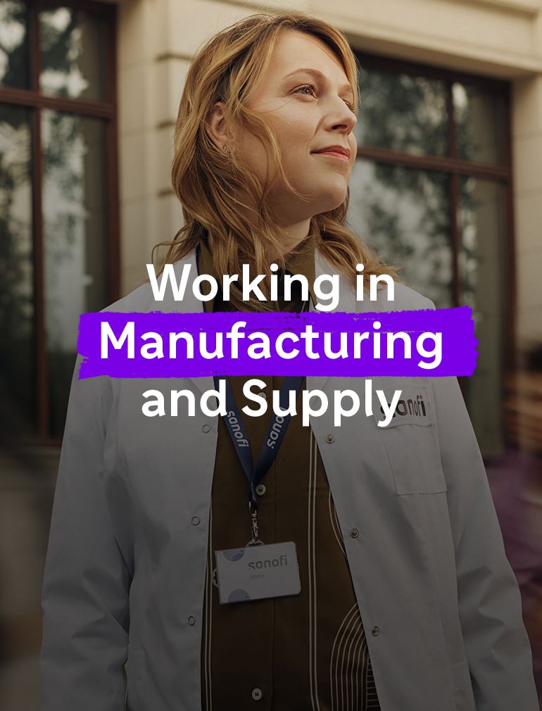 A woman in a white Sanofi lab coat and company badge looks ahead with an optimistic expression while standing outside a building. Overlay text reads: "Working in Manufacturing and Supply."​