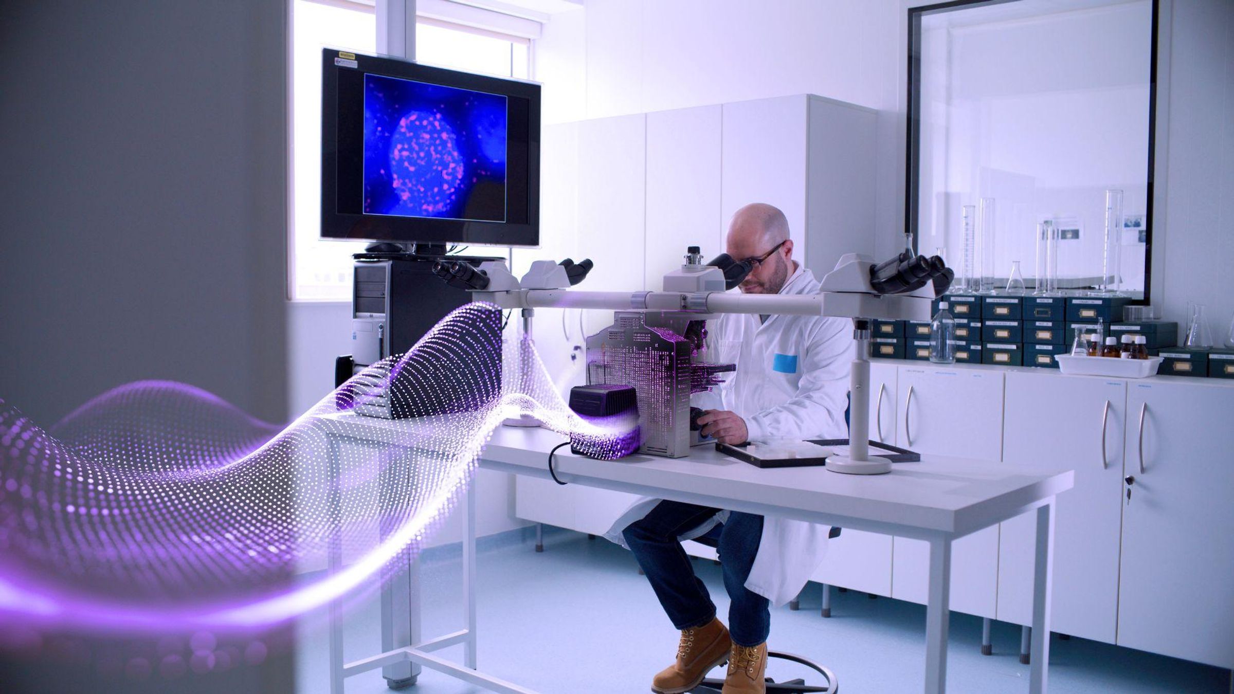 A Scientist at Vitry-sur-Seine, France, examining samples through a microscope in a laboratory with scientific equipment, a computer displaying cellular imagery, and purple data waves emanating from the microscope.