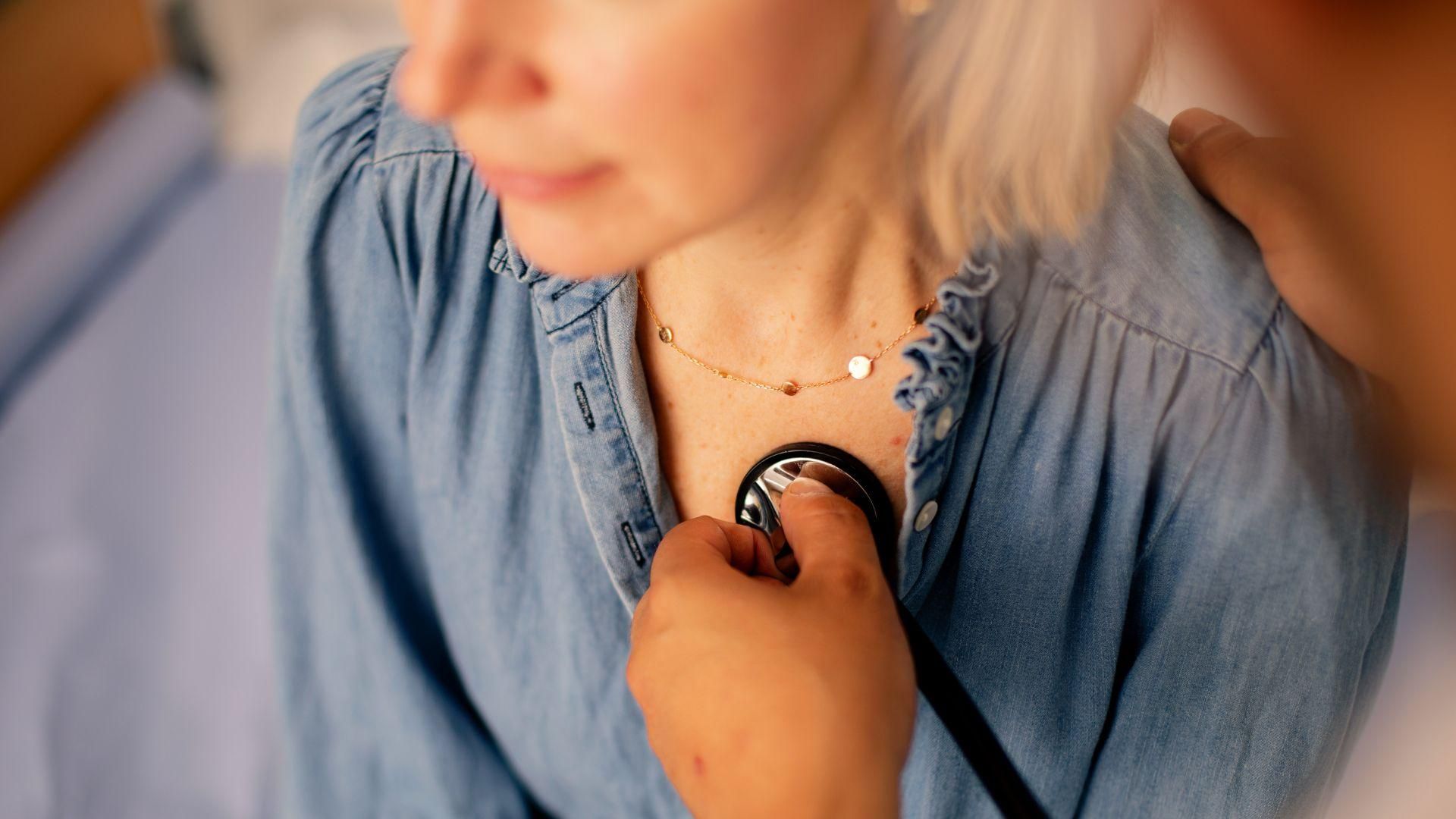 A woman getting her heart rate checked by a doctor with a stethoscope 