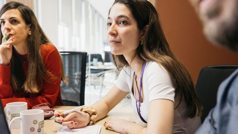 Two women and a man in a modern office space in a meeting.