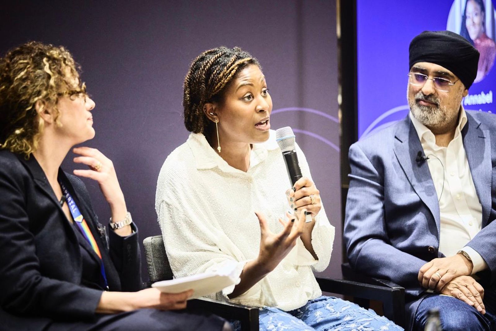 Five panellists of mixed genders seated on stage at a Sanofi event with UNESCO event in Paris. Behind them, a large screen displays the A Million Conversations logo.