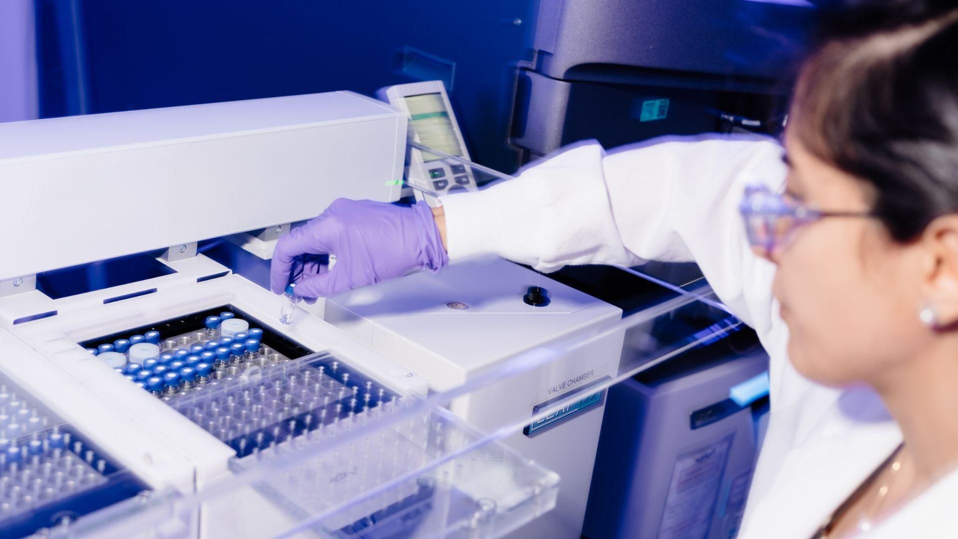 A technologist, wearing purple glove and safety glasses performing structural analysis by HDX-MS, handling samples with precision.