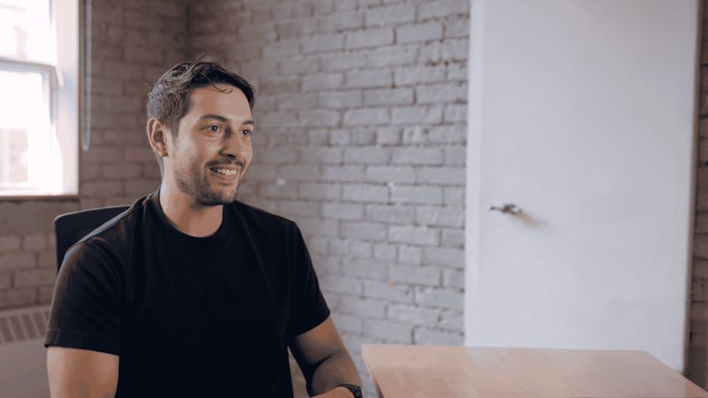 Brandon, an AI expert specializing in clinical trials, seated at a desk in a modern office with exposed brick walls and a large window providing natural light.