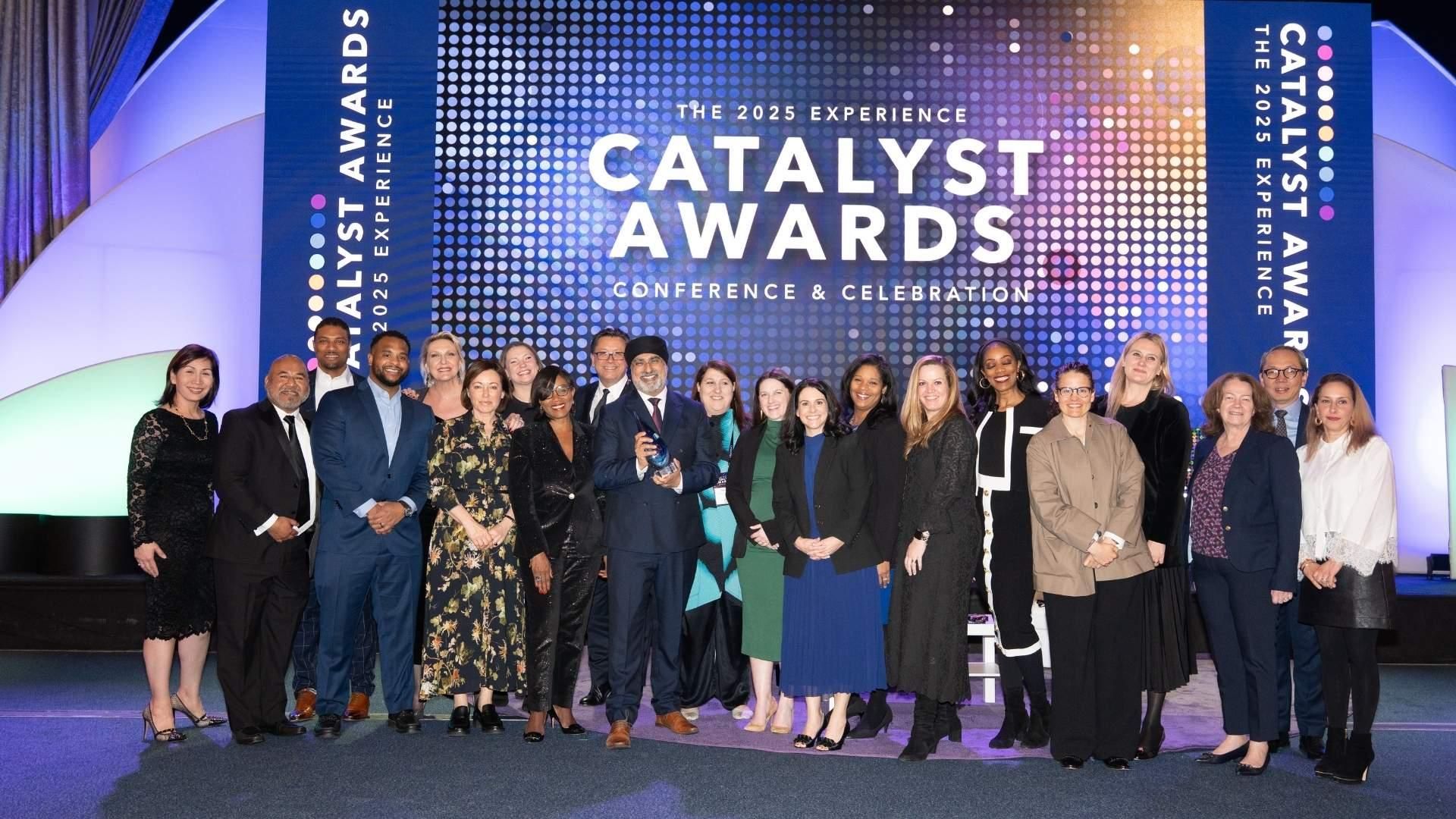 A group of Sanofi employees pose together on a stage in front of a purple backdrop for the 2025 Catalyst Awards Conference & Celebration.