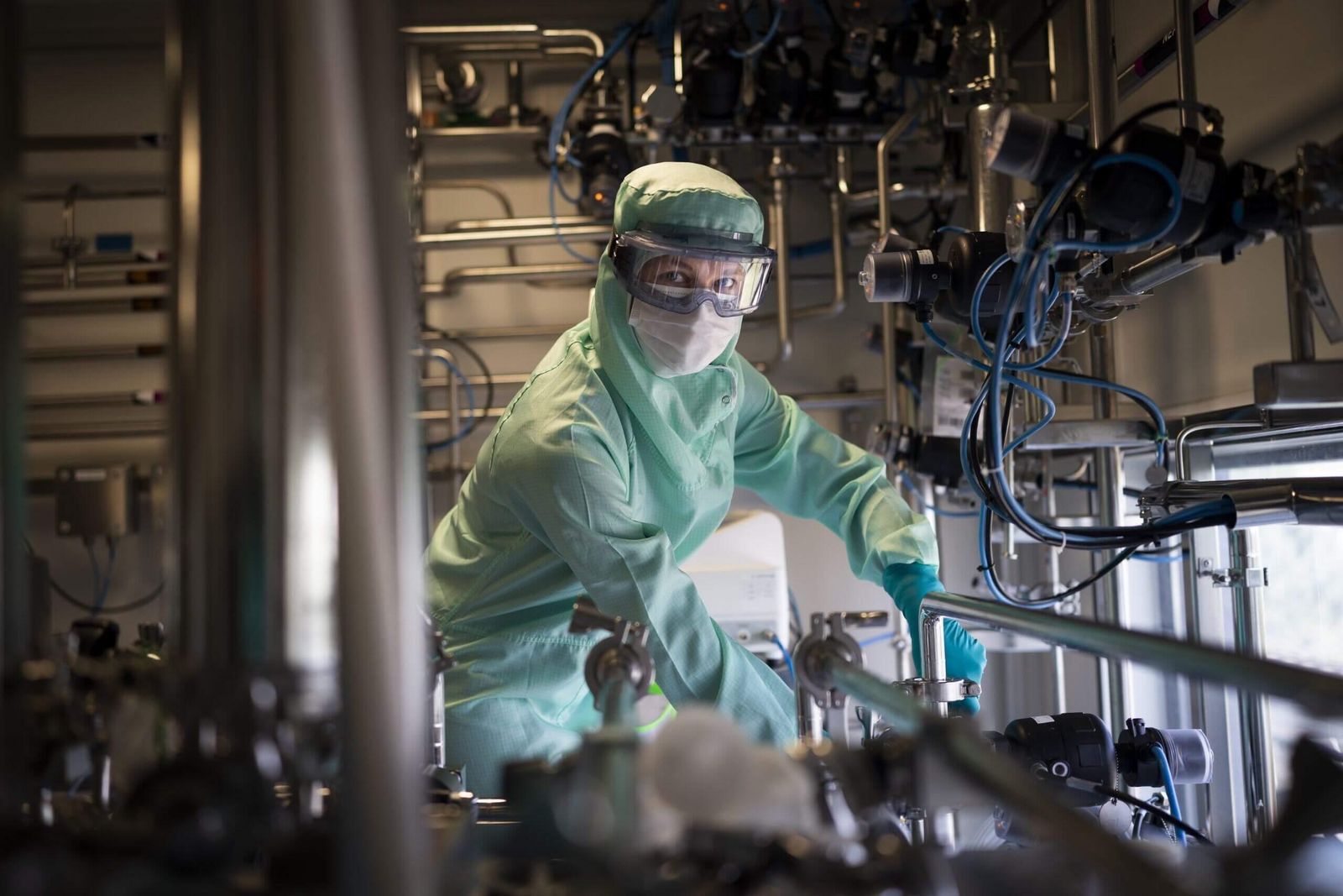 Vaccine production facility with industrial equipment and staff in protective gear