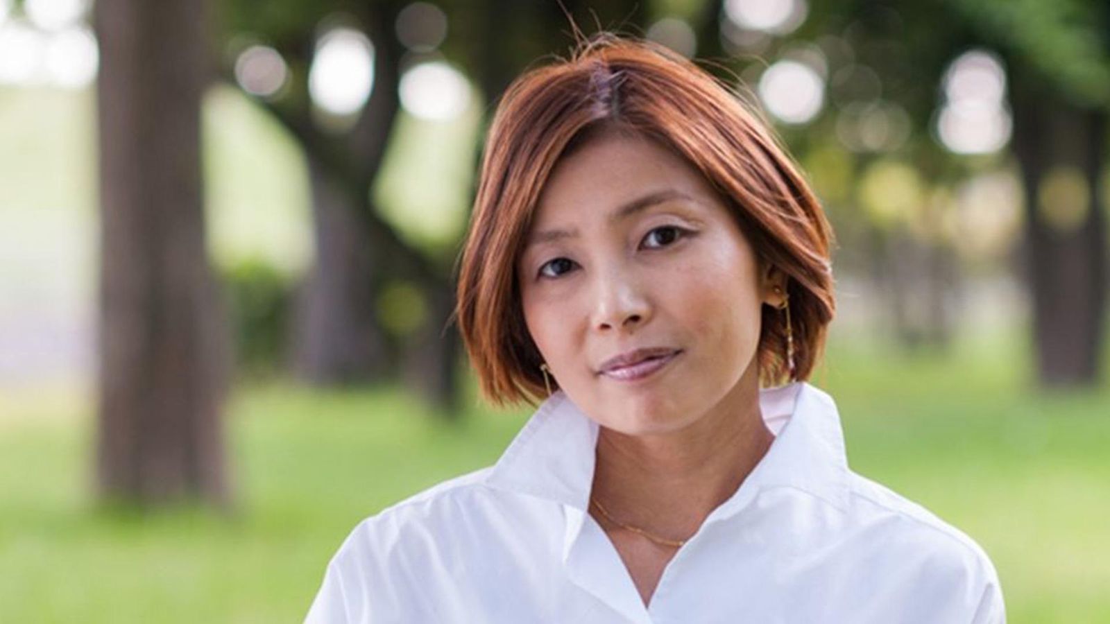 Portrait of Miwako, a Japanese woman with atopic dermatitis, in a green outdoor setting, illustrating the future of immunology and commitment to patients