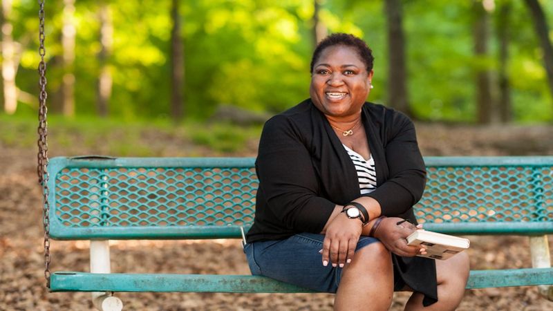 Danielle, a woman with Multiple Myeloma sitting peacefully on a park bench while reading a book.