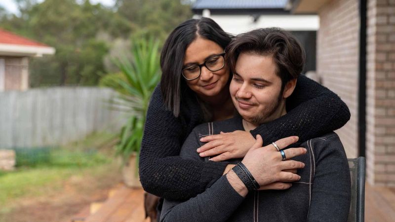 Mother and son embracing in front of a house
