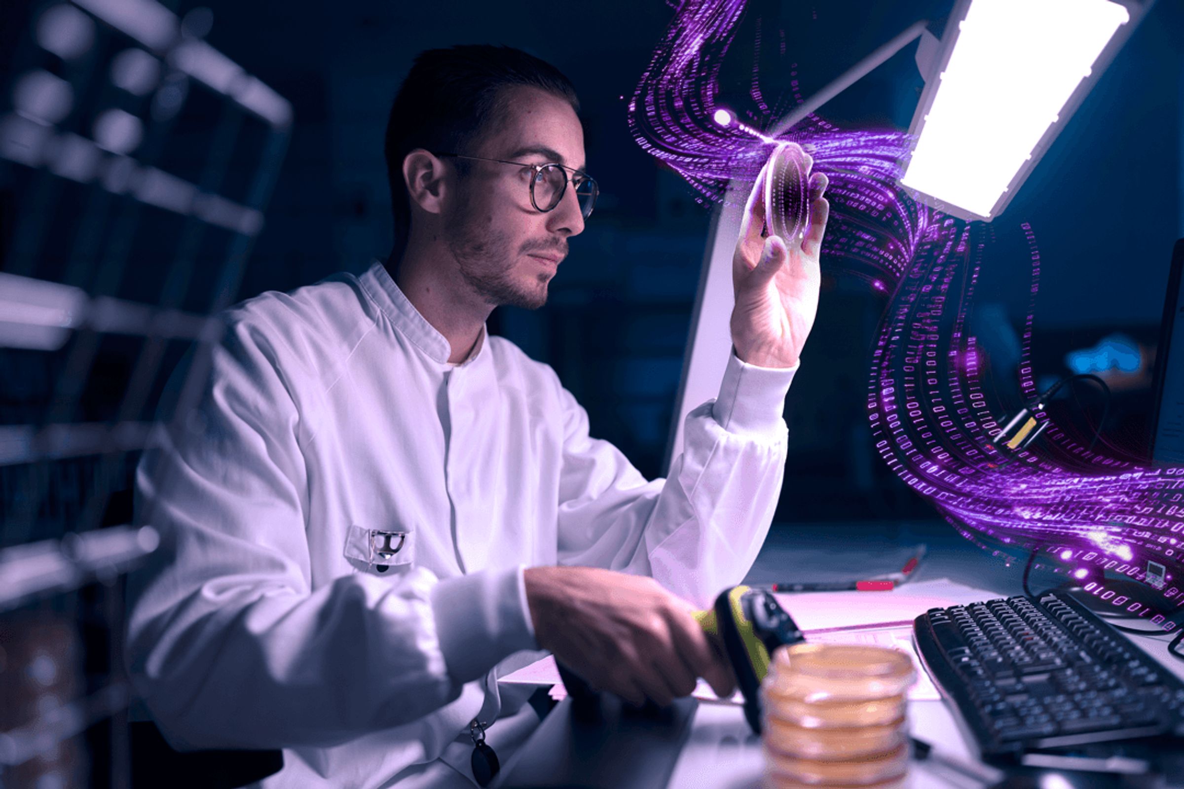 A scientist examines a petri dish under bright light in a lab. Digital data streams flow from the dish to a computer screen.