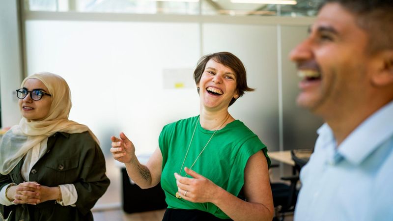 Amandine points up to focus the attention of Zeinab and Richard during a stand-up