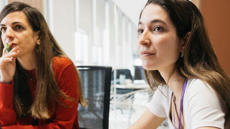 Two women and a man in a modern office space in a meeting.